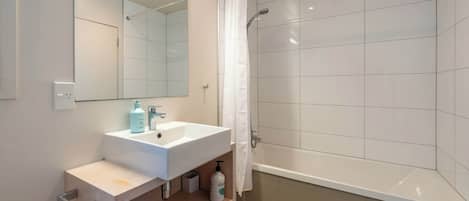 A modern bathroom with a white sink, mirror, and shower.