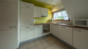 A kitchen with white cabinets, a stove, and a microwave.
