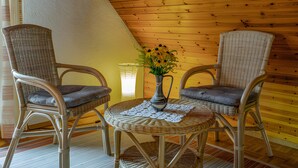 A room with two wicker chairs, a small round table, and a vase with flowers. - Studio 'Kornblümchen' with private terrace, shared garden and Wi-Fi (Oberharmersbach)
