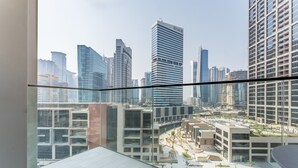 A modern building with a glass facade and a view of a cityscape with high-rise buildings. - Furnished Studio with Burj Khalifa View, Near Dubai Water Canal (Dubai)