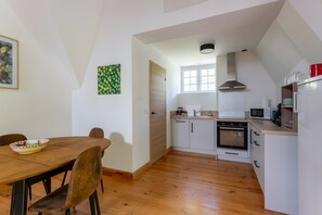 Une cuisine de taille réduite comprenant une table à manger, des chaises, un four à micro-ondes, un four et une fenêtre.
