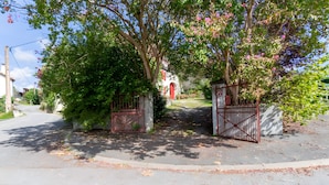 Una entrada protegida por una reja con un sendero que lleva a un edificio con una puerta roja.