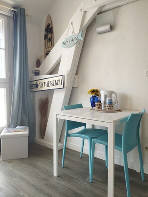 A room with a white table, teal chairs, a surfboard, and a sign reading 'Côte Plage.'