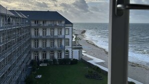 A coastal hotel with a large building, a grassy courtyard, and a view of the sea.