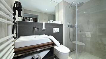 Een moderne badkamer met een glazen douchecabine, een wit wastafelmeubel en een handdoekrek.