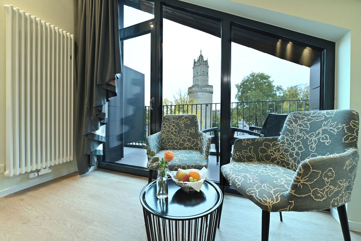 Un salon moderne offrant une vue sur un château grâce à de grandes fenêtres.
