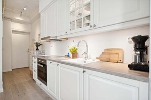 Een koelkast, een oven, kookgerei, borden en bestek