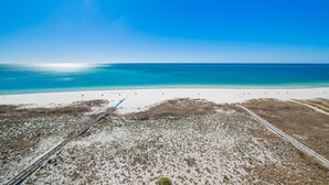 Une plage avec un ciel dégagé, une rive sablonneuse et une voie ferrée qui longe la plage.