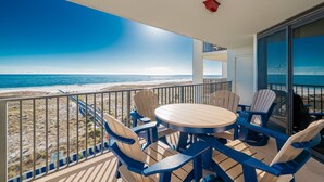 Un balcon donnant sur la plage, une table ronde avec des chaises et un luminaire rouge.