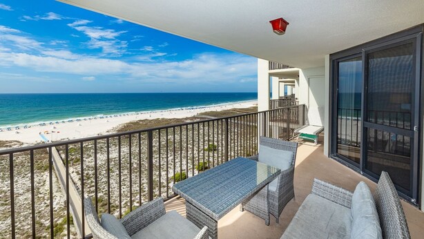 Een balkon met rieten meubilair met uitzicht op een strand.