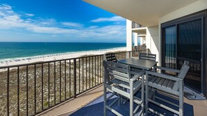 A balcony with a table and chairs overlooking a beach. - Phoenix Vi 61113 3 Bedroom Condo (Orange Beach)