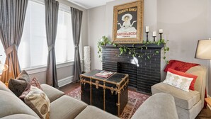 Ein Wohnzimmer mit Kamin, einer Couch, einem Couchtisch und einem gerahmten Bild an der Wand.