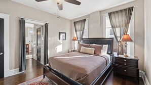 Ein Schlafzimmer mit Bett, Nachttischen, Deckenventilator und Blick ins Freie.