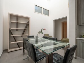 Un espace repas moderne avec une table à plateau en verre, des chaises en cuir noir et un vase orné de roses.