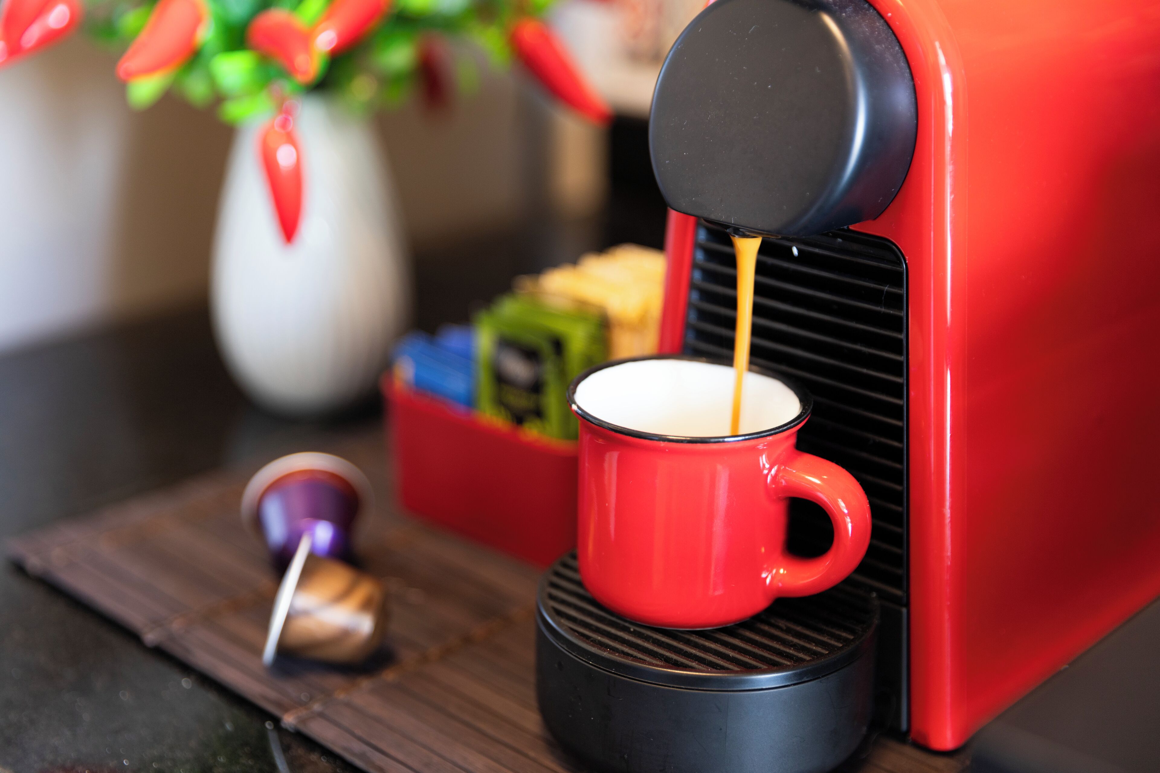A red coffee machine dispensing coffee into a red mug.