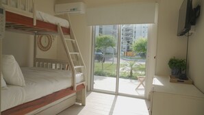 Un dormitorio con literas, una escalera, un ventanal corredizo al exterior y un televisor montado en la pared.