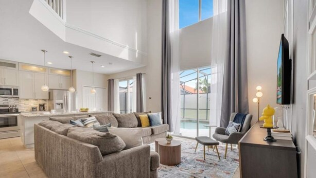 A spacious living area with a large sofa, a coffee table, and a TV on a stand.