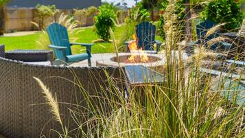 A backyard with a fire pit, outdoor seating, and a well-maintained lawn.