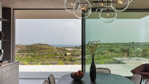 A modern dining area with a view of a hilly landscape.