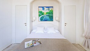 Un dormitorio con una cama, un cuadro de un paisaje urbano y una revista sobre la cama.