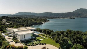 Una casa moderna con tetto piatto, piscina e vista su un lago e montagne.