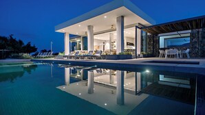 Una casa moderna con piscina, area salotto esterna e una grande sala da pranzo.