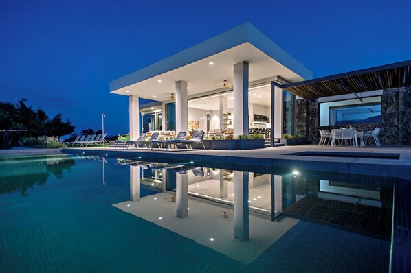 A modern house with a pool, outdoor seating, and a large dining area.