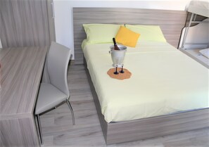 A bed with a yellow pillow, a bedside table, and a chair.