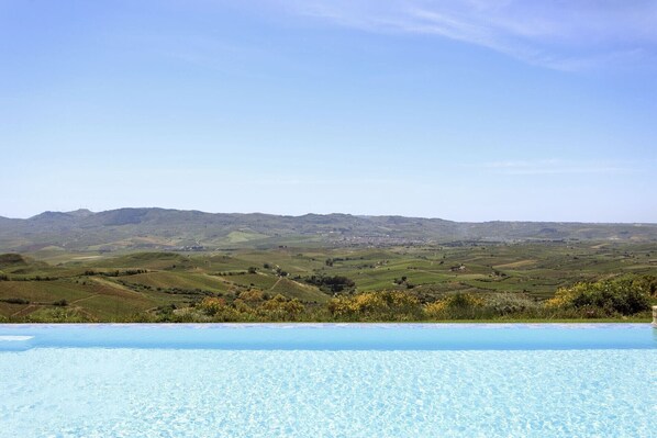 A pool with a clear view of rolling hills and a distant town.