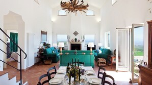A spacious living area with a dining table set for six, a green sofa, and a fireplace. - Chirchiaro - Four Bedroom Villa, Sleeps 8 (Salemi)