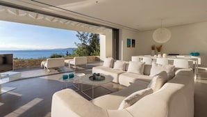 Ein modernes Wohnzimmer mit einer großen Couch, einem Couchtisch und Meerblick.