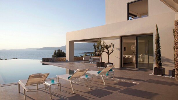 Ein Poolbereich im modernen Stil mit Liegestühlen und Meerblick.