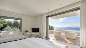 Ein modernes Schlafzimmer mit einem großen Bett, einem Fernseher und einem Balkon mit weißer Möbel.