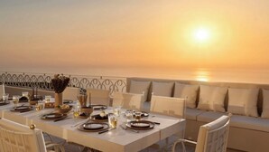 Une table dressée pour un dîner à deux, avec vue sur le coucher de soleil sur la mer.