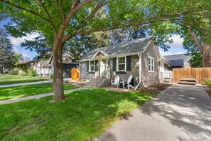 A single-story house with a front porch, a small deck, and a well-maintained lawn. - Shade Tree Bungalow Old Town, Yard & Garage (Fort Collins)