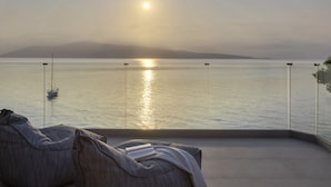 A balcony with a view of a calm sea and a boat, a clear sky, and a distant mountain range. - Eolia - Three Bedroom Villa, Sleeps 6 (Nikiana)