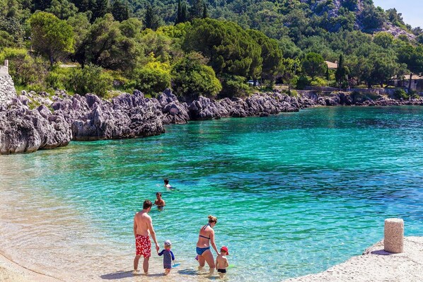Un mar turquesa y transparente con costas rocosas y abundante vegetación al fondo.