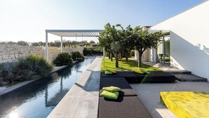 A modern outdoor patio with a pool, seating areas, and a pergola.