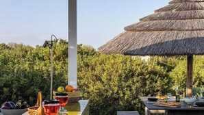 An outdoor dining area with a tiled bar, stools, and a thatched-roof structure.