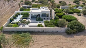 A modern house with a pool, surrounded by landscaped gardens and a view of the countryside.