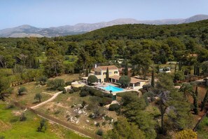 Eine großzügige, moderne Villa mit Schwimmbad, umgeben von dichtem Wald und Bergen im Hintergrund.