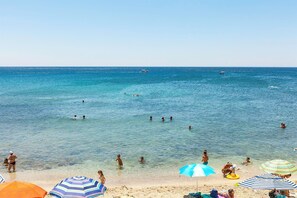 A beach with clear blue water, people swimming and sunbathing, and colorful umbrellas. - Castello di Caprarica (Tricase)