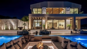 A modern house with a swimming pool, outdoor seating, and a fire pit.