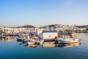 A harbor with boats docked, a small white building, and white buildings in the background.