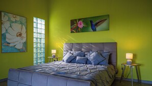 Une chambre à coucher avec un grand lit, deux tables de chevet et des œuvres d’art accrochées aux murs.