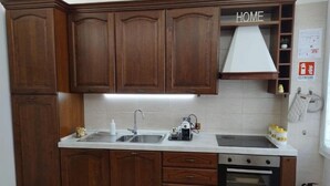 A kitchen with wooden cabinets, a double sink, a stove, and a white countertop. - Alcinque - Your home in Rome, in the heart of San Giovanni (Roma)
