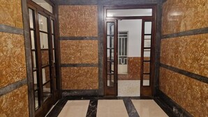 A hallway with marble walls and a striped floor, leading to a door with a glass panel. - Alcinque - Your home in Rome, in the heart of San Giovanni (Roma)