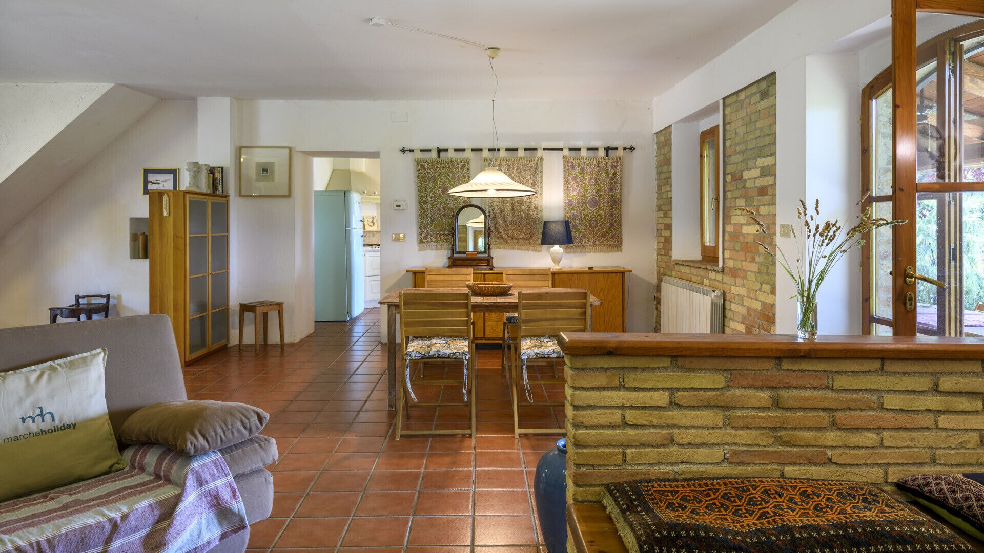 A spacious living area with a dining table, a sofa, and a kitchen in the background.