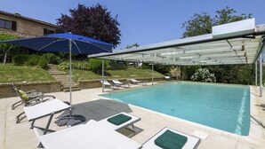 Una piscina con sillas de descanso y una zona techada.