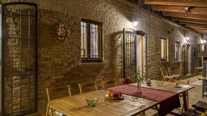 Un comedor rústico con pared de ladrillo, mesa de madera y barrotes en las ventanas.